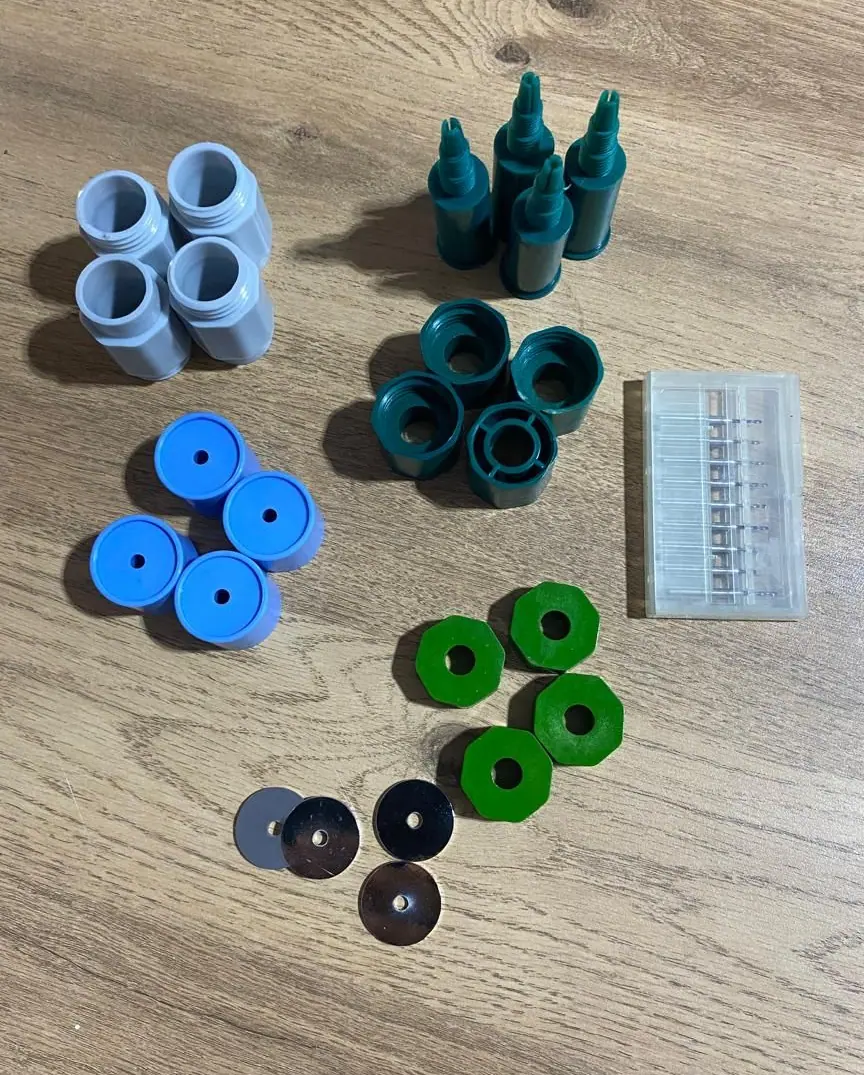 Hobby Helper mechanism parts, caps, collars and a case of drill bits laid out on a table
