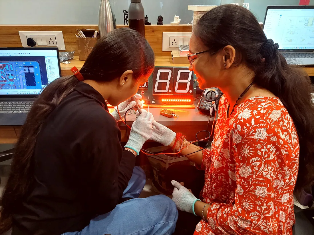 Two CADLETE engineers in ESD gloves assembling and testing pickleball scoreboard electronics at the bench