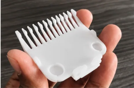 White 3D printed prototype of a trimmer guard held in a hand