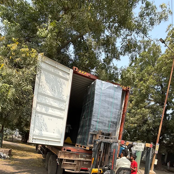 A shipping container being loaded onto a truck for export