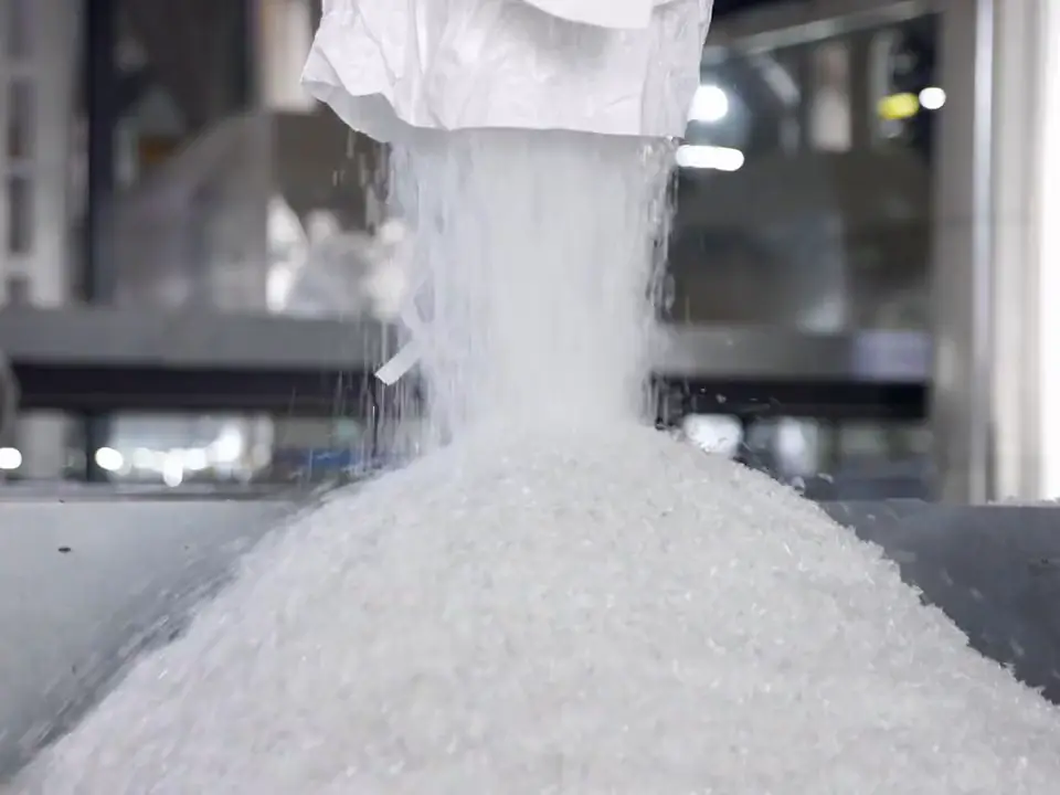 Plastic granules pouring into a hopper, then injection-molded preforms dropping from a molding machine