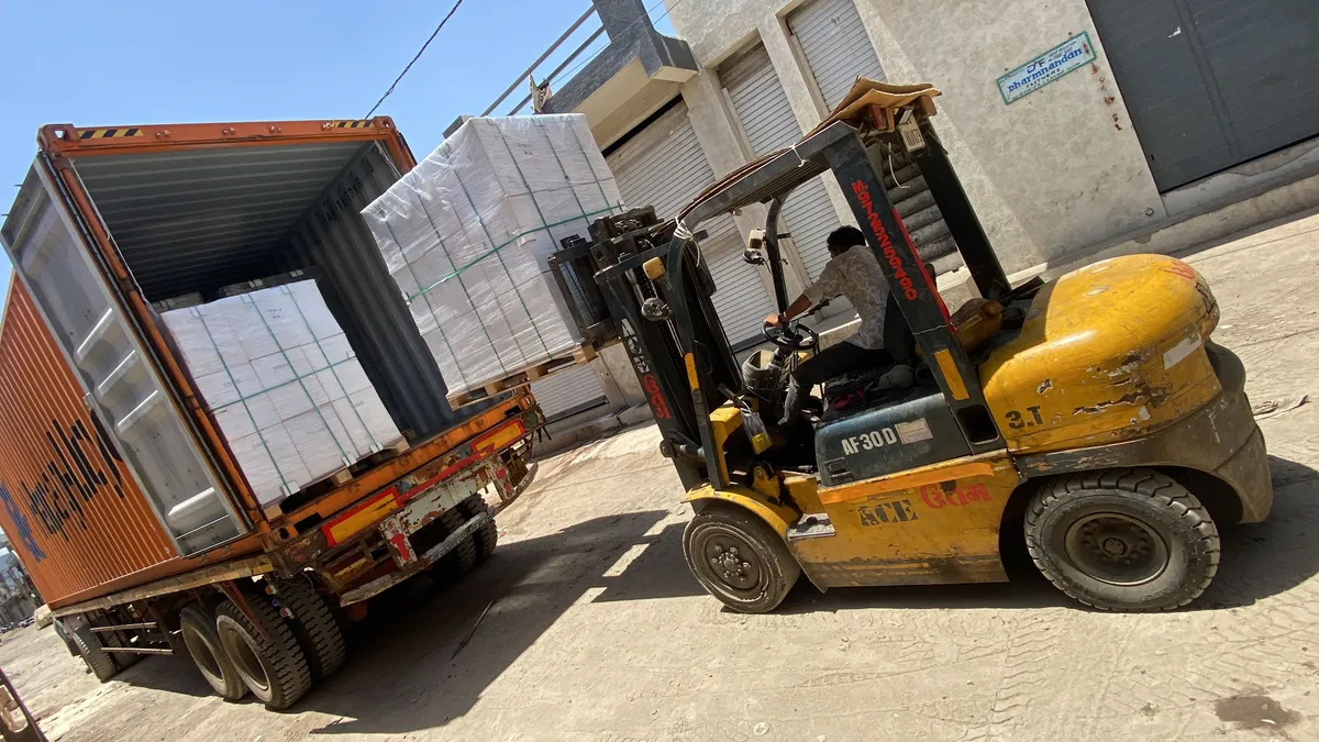 Forklift loading carton pallets into a 40 ft container