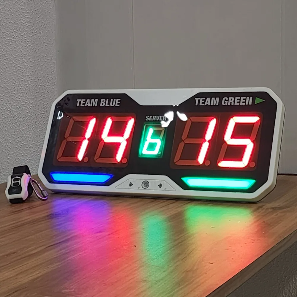 Final redesigned pickleball scoring unit on a wooden surface with its wristband controller