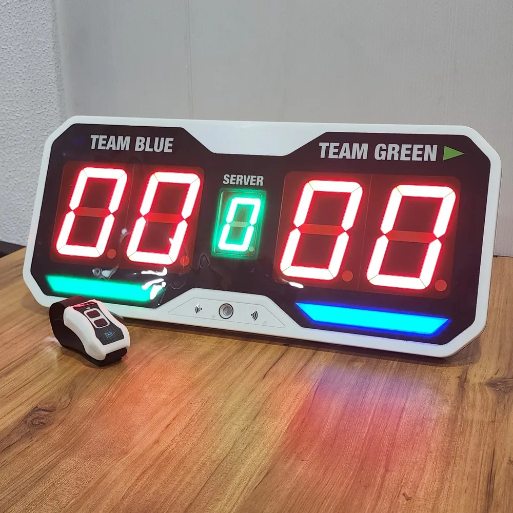 Finished pickleball scoring unit and wristband controller on a wooden table, both showing a live score